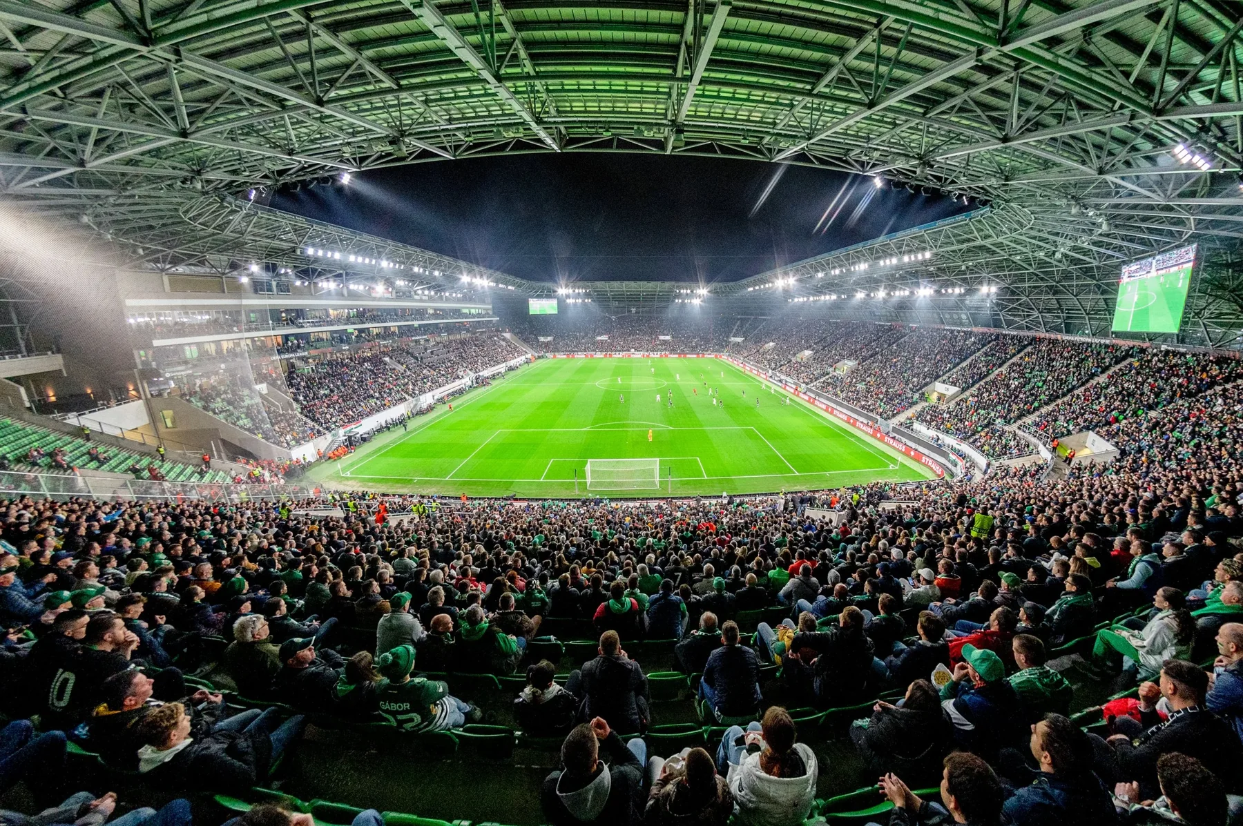 Supporters watching a European qualifying match in a floodlit stadium